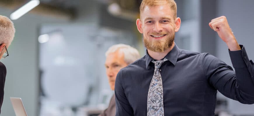 portrait-smiling-businessman-clenching-his-fist-while-team-discussing-background