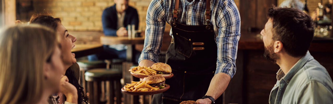 happy-waiter-serving-food-group-cheerful-friends-pub.jpg