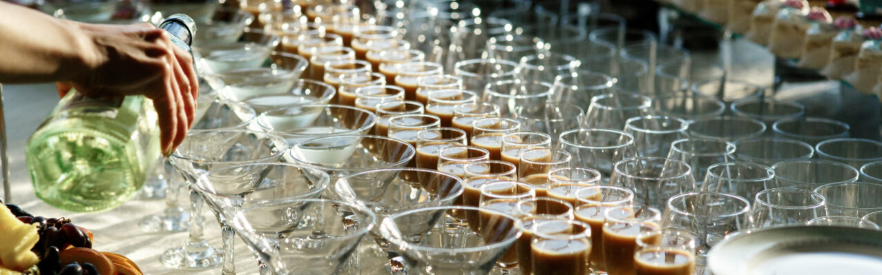 man-pours-martini-cocktail-glasses-dinner-table.jpg